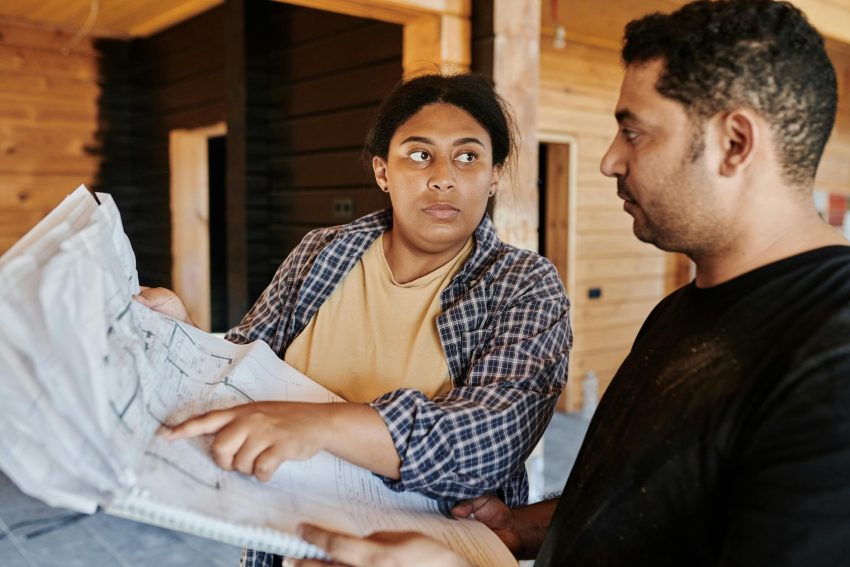 man in black crew neck t shirt looking on a blueprint beside a woman